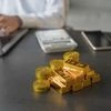 Stack of physical gold bullion bars on a corporate desk with a calculator and laptop representing wealth management and valuation.
